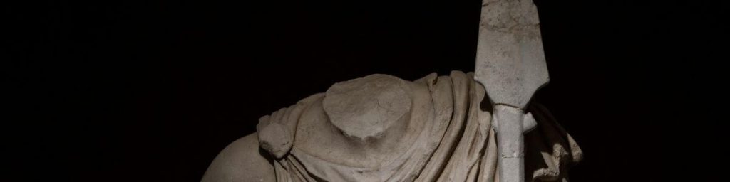 Headless ancient statue against a dark, moody background.