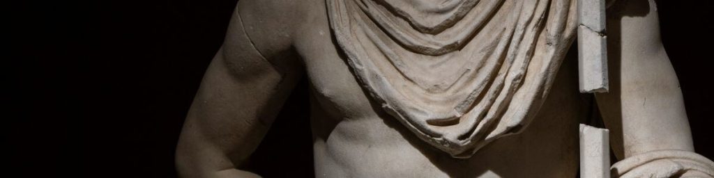 Partial view of an ancient statue showing the torso and a spear.