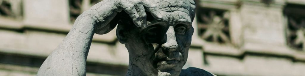 Close-up of a pensive ancient statue with a hand resting on its temple.